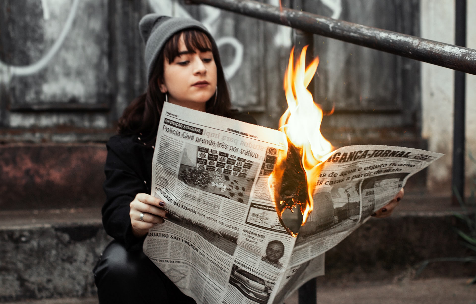 Woman reading a newspaper while the paper is on fire